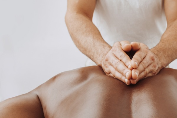 Two hands, cupped over a persons back giving them a massage.