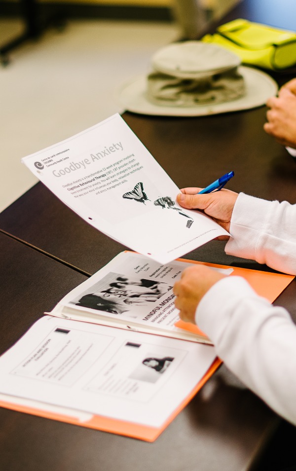 Hands showing a person adding some paperwork about Anxiety into an orange binder.