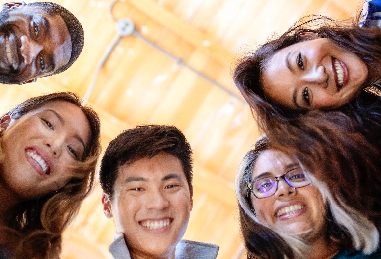 Three women and 2 men in a circle looking down at the person taking the photo.